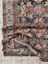 Hand-knotted vintage Persian rug folded on wooden floor