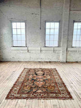 Hand-knotted vintage Persian rug on wood floor in room with big windows