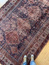 Person standing on a Hand-knotted antique Persian Afshar area rug on a wood floor