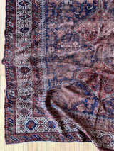 Corner of a hand-knotted antique Persian Afshar area rug with medallions and an allover animal motif