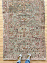 Person stading on a hand-knotted antique Persian Mahal area rug with allover botanical motifs on a celadon green field
