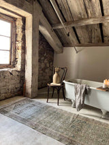 Rustic bathroom with clawfoot bathtub, wooden beams, and a vintage runner rug