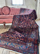 Colorful vintage Persian runner rug draped over a pink velvet sofa