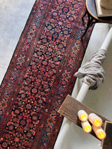 Colorful vintage Persian runner rug near a clawfoot tub with candles