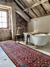 Colorful vintage Persian runner rug in a rustic bathroom with clawfoot tub