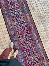 Person standing on a olorful vintage Persian runner rug