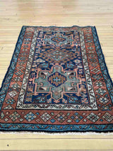 Antique Persian accent rug on a wooden floor