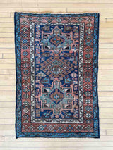Antique Persian accent rug with intricate patterns on a wooden floor