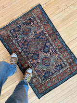 Person with yellow shoes standing on an Antique Persian accent rug
