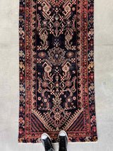 person standing on a vintage Persian Hamadan runner rug with intricate pattern and navy blue field