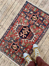 Person wearing mustard colored shoes stepping onto colorful vintage rug on a wooden floor
