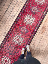 Person standing on a Red Vintage Persian Runner Rug with medallions a