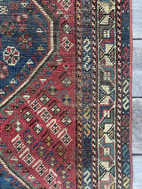 Close-up of border of an antique hand-knotted Persian area rug with a geometric medallion pattern, featuring a bird motif