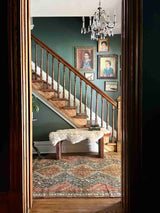 Entryway with staircase and an antique hand-knotted Persian area rug with a geometric medallion pattern, featuring a bird motif