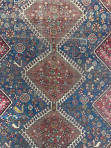 Close-up of Antique hand-knotted Persian area rug with a geometric medallion pattern, featuring a bird motif