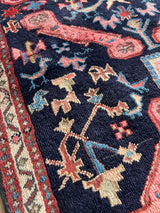 Close-up of a colorful vintage Caucasian Kuba accent rug with animal motifs and navy field