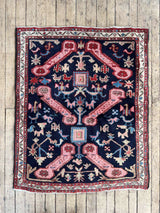 Vintage Caucasian Kuba accent rug with animal motifs and navy field on a wood floor