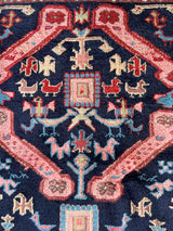 Close-up of a intricately designed vintage Caucasian Kuba accent rug with animal motifs and navy field