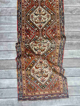 Draped vintage Persian runner rug with ivory repeating medallions and a bird and boteh motif on a brick red field