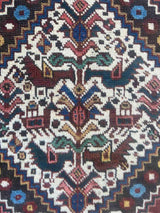 Close-up of a vintage Persian runner rug with ivory repeating medallions and a bird and boteh motif on a brick red field