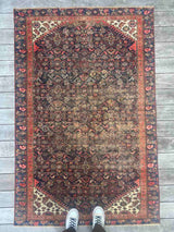 Person standing on an Antique Persian area rug with an allover motif on navy field
