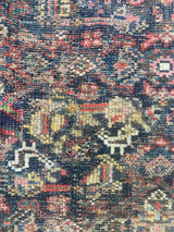 Close-up of the repairs on an Antique Persian area rug with an allover motif on navy field