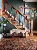 Entryway with staircase, antique art, and an Antique Persian area rug with an allover motif on navy field