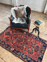 Vintage Persian area rug botanical motifs with chair, sheepskin, and table