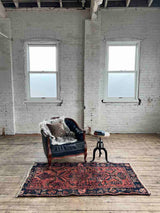 Vintage Persian area rug botanical motifs with a chair and side table