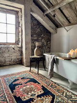 Rustic bathroom with stone walls, wooden beams, and a Colorful vintage area rug