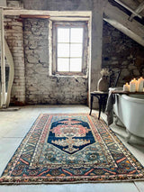 Room with stone walls, a large window, and a pColorful vintage area rug
