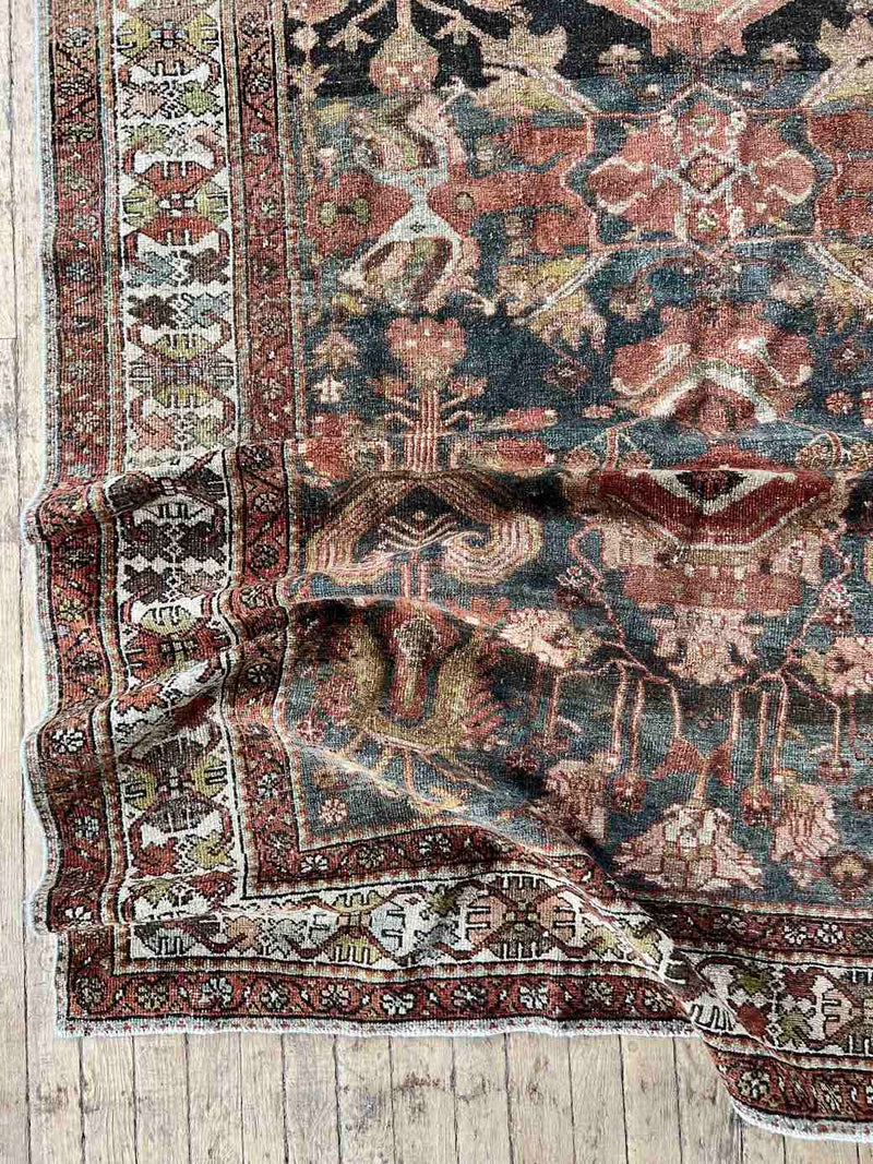 Hand-knotted vintage Persian rug folded on wooden floor