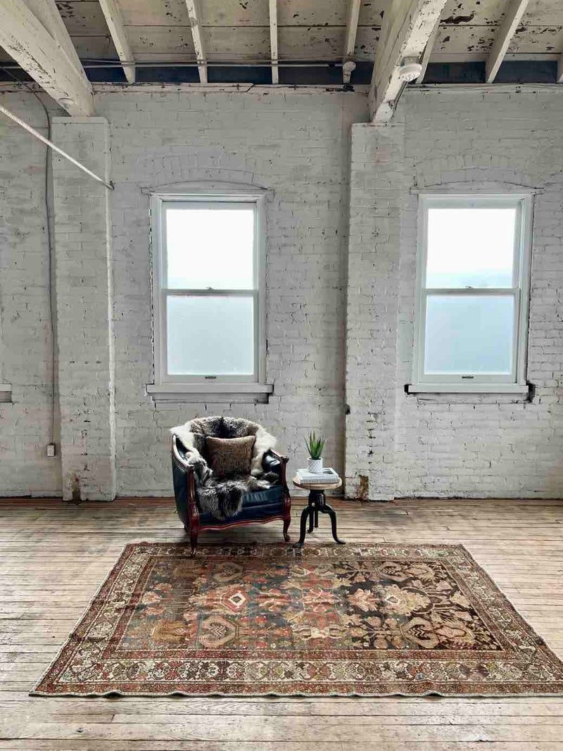 Hand-knotted vintage Persian rug in a living room with armchair and sheepskin
