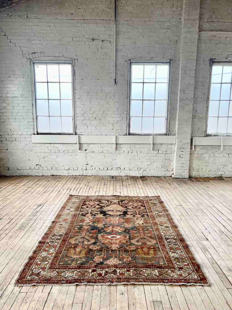 Hand-knotted vintage Persian rug on wood floor in room with big windows