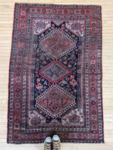 Vintage Persian rug with colorful medallions on a wooden floor
