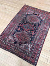 Vintage Persian rug with colorful medallions on a wooden floor