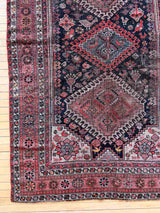 Vintage Persian rug with colorful medallions on a wooden floor