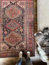 Person standing on a vintage Persian rug with colorful medallions beside a beige sofa