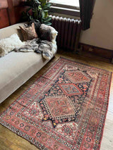 Vintage Persian rug with colorful medallions  beside a beige sofa with a sheepskin throw