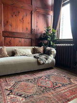Vintage Persian rug with colorful medallions with a beige sofa, sheepskin throw and pillows