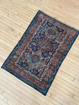 Antique Persian accent rug  on a wooden floor
