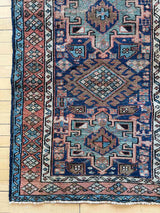 Antique Persian accent rug with intricate patterns on a wooden floor