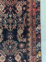 Close-up of a vintage Persian Hamadan runner rug with brick red and peach herati motif and navy blue field 