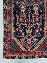 Corner of a vintage Persian Hamadan runner rug with brick red and peach herati motif and navy blue field