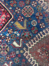 Close-up of border of an antique hand-knotted Persian area rug with a geometric medallion pattern, featuring a bird motif