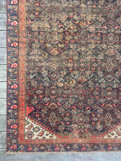 Corner of an Antique Persian area rug with an allover motif on navy field