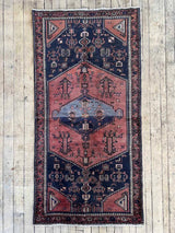 Vintage Persian Saveh  area rug with dusty pink and blue medallions and a navy field on a wooden floor