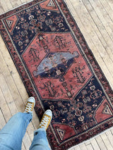 Person wearing yellow sneakers standing on a Vintage Persian Saveh  area rug with dusty pink and blue medallions and a navy field