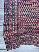 Close-up of an Antique Persian area rug draped across the floor