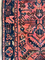 Close-up of a Vintage Persian area rug botanical motifs and a berry colored field